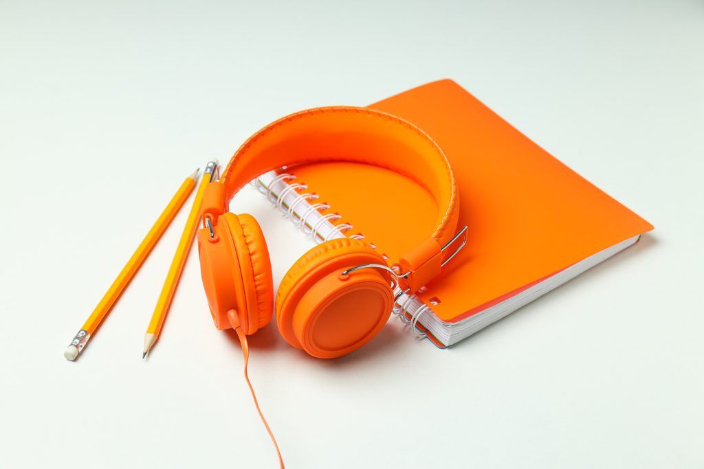 On top, large, bright orange headphones, on a light background.