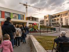 Roditelji s djecom i starije osobe stoje u redu ispred novog vrtića dok se u pozadini vidi moderna zgrada i gradilište, ilustrirajući nedostatak mjesta unatoč ulaganjima