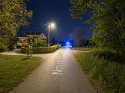 Prazna ulica noću s vidljivim policijskim svjetlima u daljini.