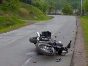 Srušeni motocikl leži na kolniku nakon prometne nesreće na zavoju ceste, bez vidljivih sudionika.