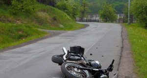 Srušeni motocikl leži na kolniku nakon prometne nesreće na zavoju ceste, bez vidljivih sudionika.