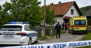 Policijski automobil i vozilo hitne pomoći ispred kuće u selu, uz policijsku traku tijekom očevida