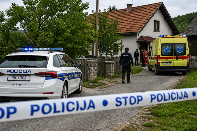 Policijski automobil i vozilo hitne pomoći ispred kuće u selu, uz policijsku traku tijekom očevida