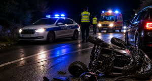 Noćna prometna nesreća na mokroj cesti s prevrnutim četverociklom i prisutnim vozilima hitnih službi