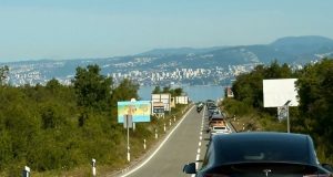 Kolona vozila na cesti prema unutrašnjosti s pogledom na Kvarner i Rijeku u pozadini