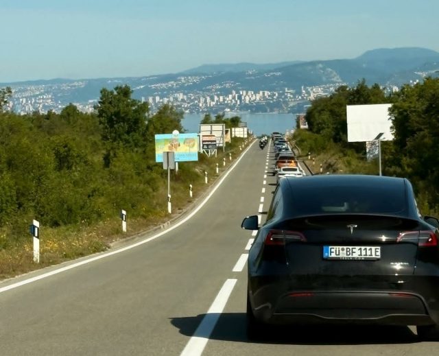 Kolona vozila na cesti prema unutrašnjosti s pogledom na Kvarner i Rijeku u pozadini