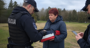 Ilustracija policijske kontrole žene u Latviji nakon viralne snimke povezane s torbicom u bojama koje podsjećaju na rusku zastavu.